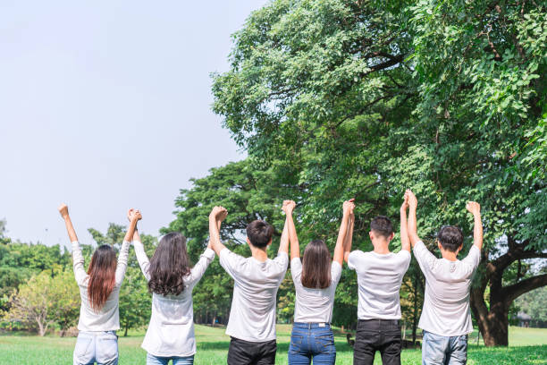 istock Six people standing and holding hands in the park forest at outdoors with green tree background. concept of teamwork, spirit, meeting; seminar; activity and community. 950956418