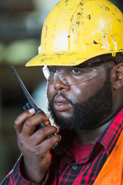 istock African-American man with hardhat, on walkie-talkie 950956514