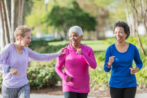 istock Three mature women power walking together in park 950961708