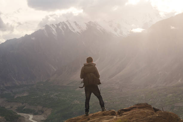 istock Traveller with backpack standing on mountain peak, enjoying beautiful sunset and valley view. Travel lifestyle and achievement success concept 950961760