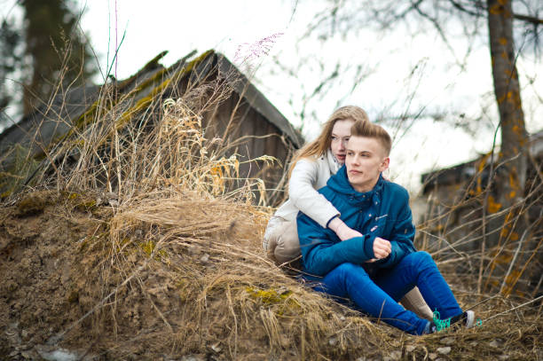 Taken during the golden hour, siblings playing on the field spending time together. Cool big brother hugs and kisses his little sister, who is beaming and shining with joy.