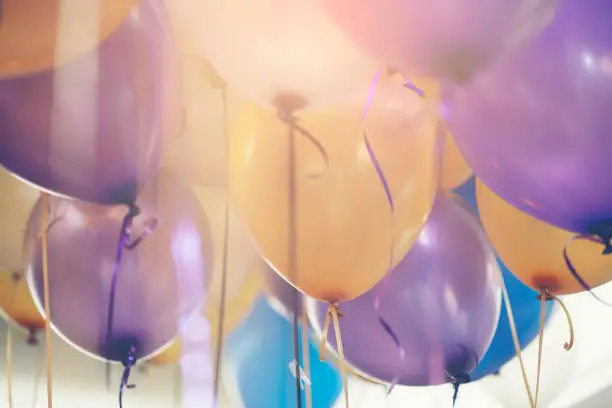 Photo of Balloon in birthday party background.Multi colour (yellow,blue,violet,purple) helium Ballon with string and ribbon in celebrate wedding day.Concept of balloon in wedding and birthday party.