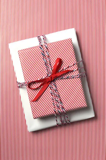 Top view of a Christmas present wrapped with red striped paper on a background of the same paper.