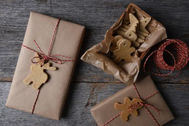 Top view of Christmas Presents with Holiday Shaped Cookies on a rustic wood background.