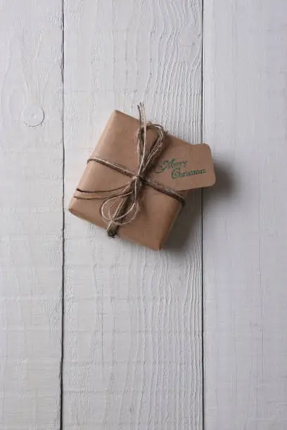 Top view of a single plain paper wrapped Christmas present with a tag stamped with Merry Christmas.