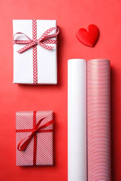 Two Wrapped presents with matching paper rolls and a red heart.