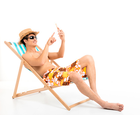 Relaxed man sitting in lounger chair and using smart phone