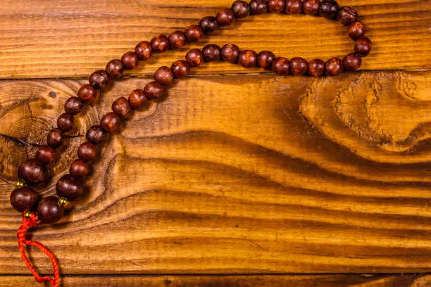 Photo of Brown rosary on the wooden table. Top view