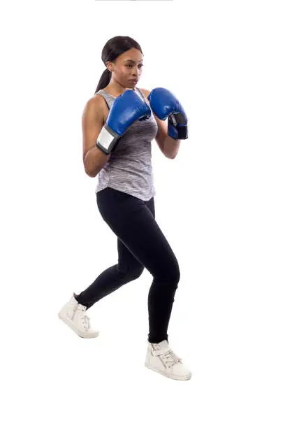 Black female isolated on a white background wearing boxing gloves working out with box aerobics cardio.  She is posing with punches and depicts fitness or self-defense and martial arts.