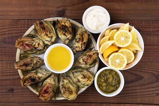 High angle view of a plate full of grilled artichokes on a rustic restaurant table.