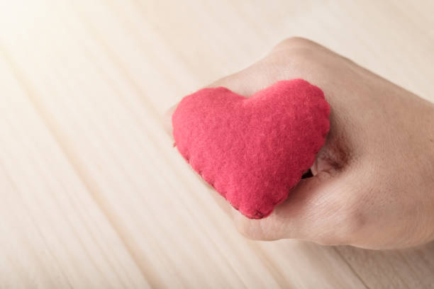 istock Red single heart with hand on wooden background 950986294
