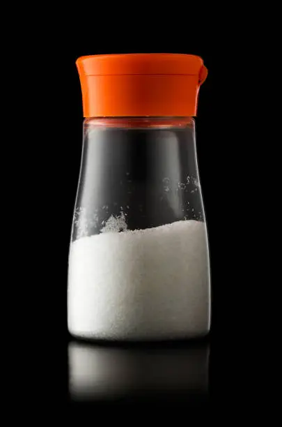 A plastic shaker of MSG (monosodium glutamate) flavour enhancer isolated on black background with clipping path