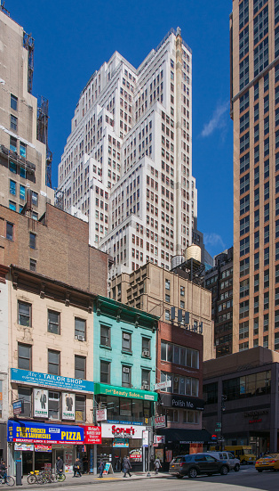 New York, U.S.A. - April 20, 2018: Midtown masonry Skyscrapers in bright Spring sun against blue sky taken on 6th Avenue between 37th and 38th Streets