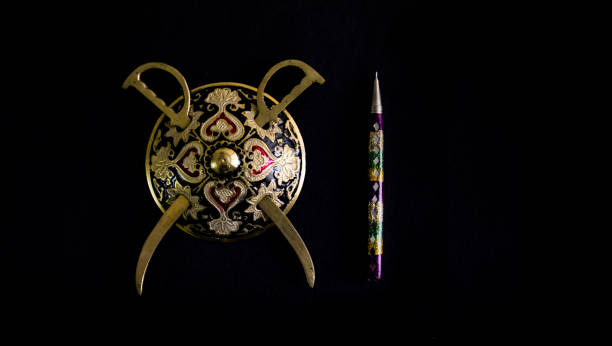 istock decorated round sword and shield and pen isolated in black background with copy space for text.antique artefact 950988160