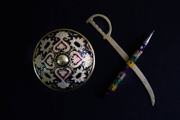 pen is mightier than sword concept by decorated round sword shield and pen in black background .antique artefact