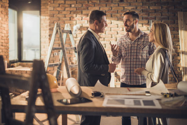 istock Smiling architect talking to couple during home improvement process. 950995500