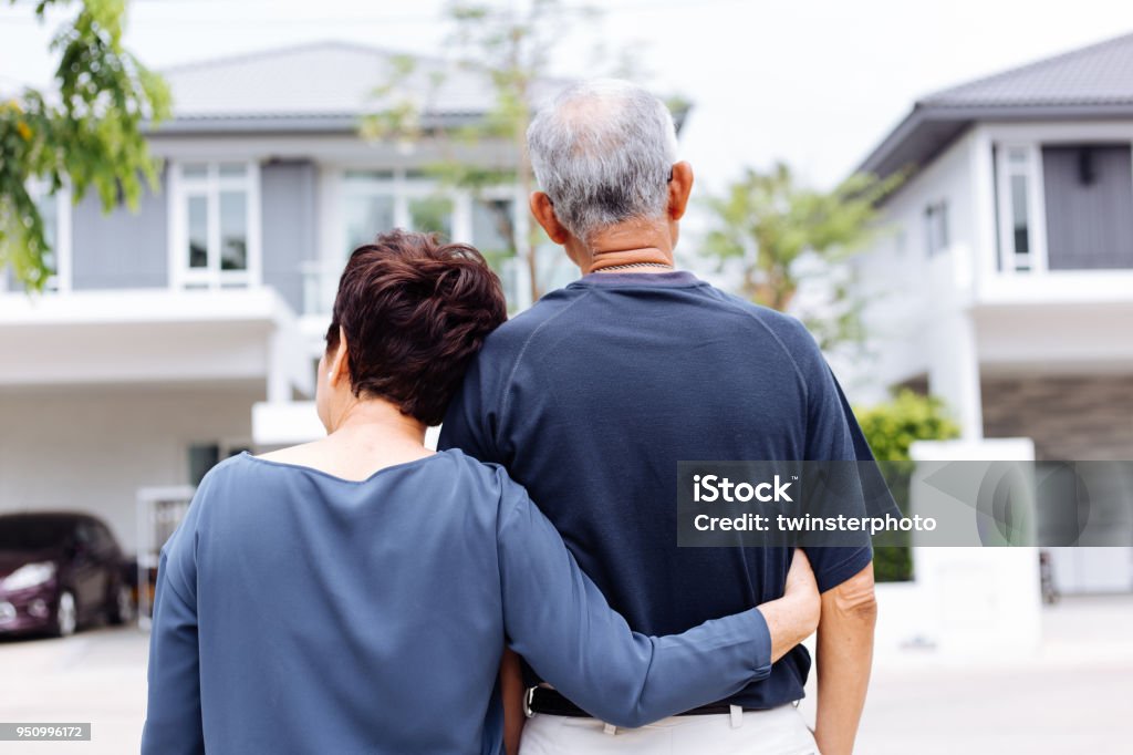 Feliz pareja senior por detrás mirando en frente de casa y coche - Foto de stock de Casa libre de derechos