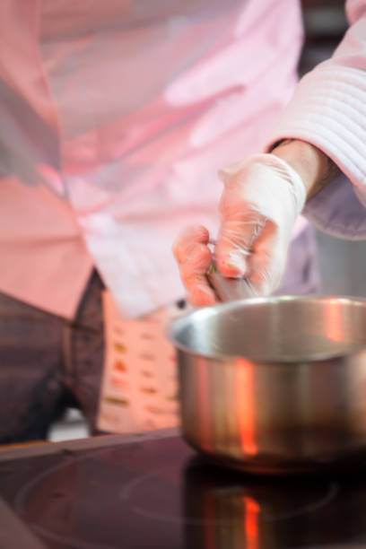 istock Cook's hand in white gloves and robe keeps the pan over the elec 951004424
