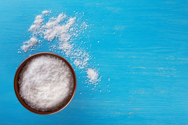 istock Clay brown bowl with salt on blue background 951012240