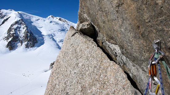 bolt and quick draw with climbing equipment on an exposed and steep climbing route in the French Alps with Mont Blanc in the background near Chamonix in the French Alps