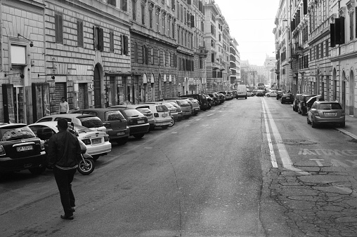 A street in thessaloniki greece empty free of human traffic. Several cars parked and a man on the foreground looking ahead