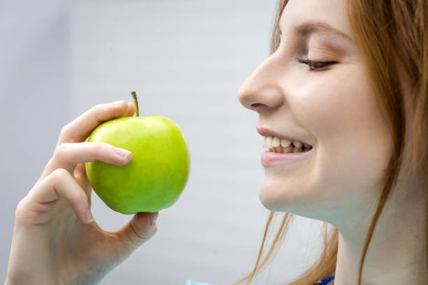 istock Young woman with healthy tooth biting green apple 951023852