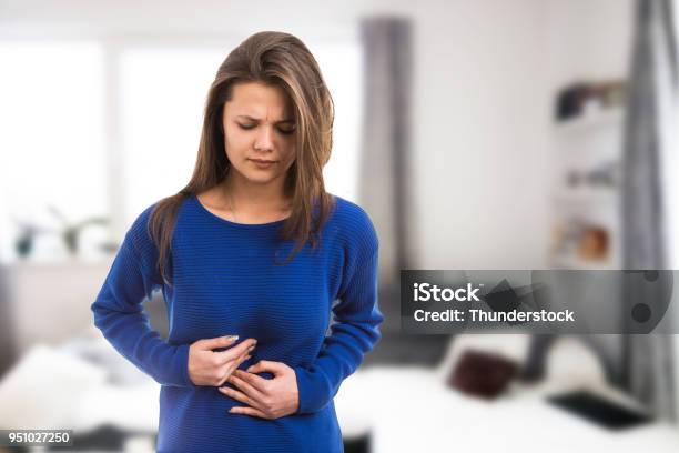 Joven Mujer Que Sufre Dolor De Estómago Foto de stock y más banco de imágenes de Abdomen - Abdomen, Estómago, Ácido