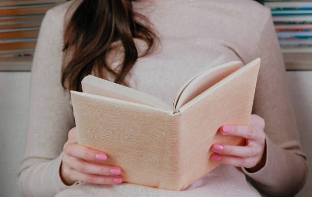 istock Unrecognizable young brunette woman looking through a book. 951029682