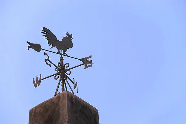 Wind vane in a form of a rooster on the top of a roof.