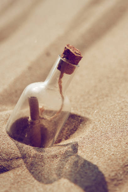 istock A bottle with a message is thrown by a wave on a sandy beach. Sandy background. 951044354