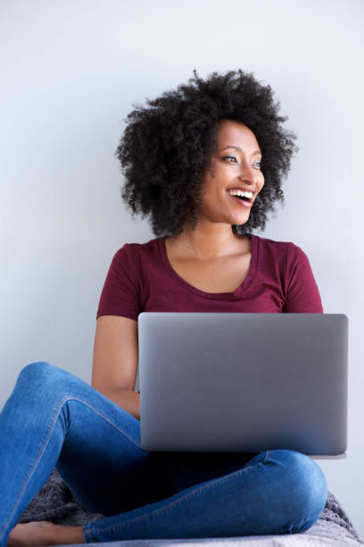 istock smiling black woman relaxing at home with laptop computer 951045096