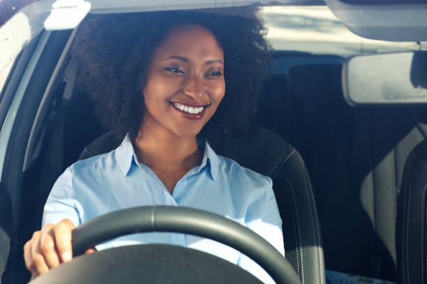 happy young african american woman driving a car and smiling stock photo