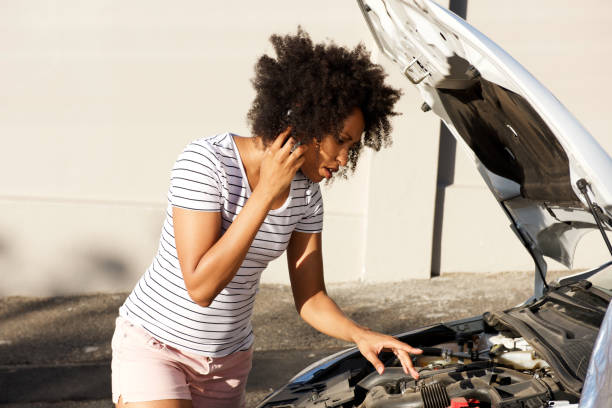 junge afrikanische frau kaputt auto auf der straße geparkt und ruft um hilfe - autopanne stock-fotos und bilder