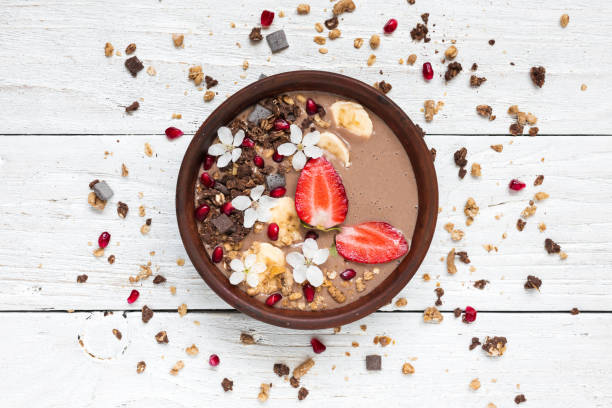 kakao banan protein smoothie bowl med choklad granola, jordgubbar och granatäpple frön dekorerad med blommor - yoghurt chocolate bowl bildbanksfoton och bilder