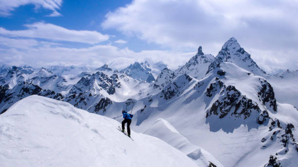 мужской лыжник бэккантри катается на лыжах вниз с высокой вершины в бэккантри швейцарских альп на лыжном туре зимой и действует немного гл� - mountain switzerland scuol mountain peak стоковые фото и изображения