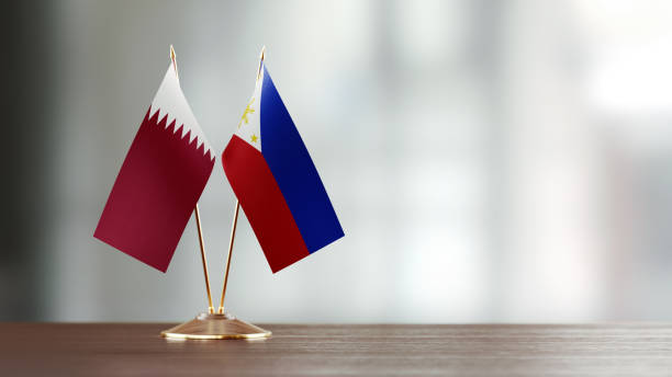 istock Qatari And Philippines Flag Pair On A Desk Over Defocused Background 951054944
