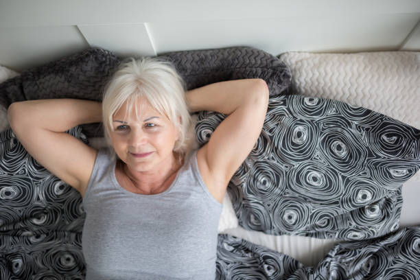 istock Senior lady lying in bed dreaming 951059070