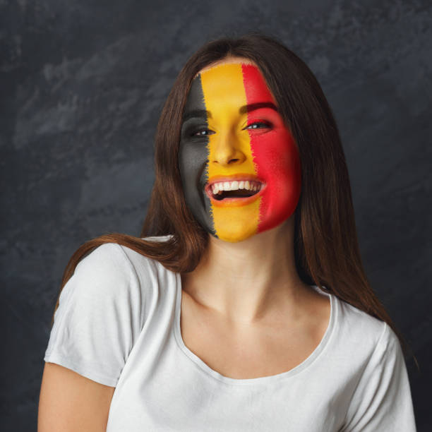 istock Young woman with Belgium flag painted on her face 951059424