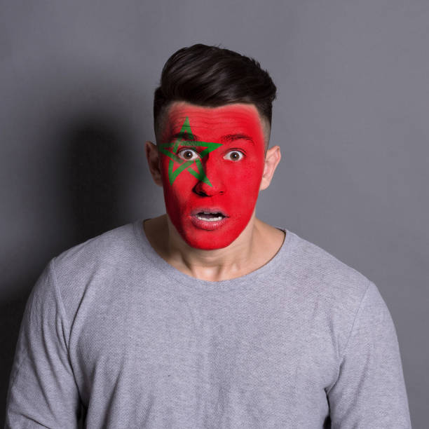 istock Young man with Morocco flag painted on his face 951059740