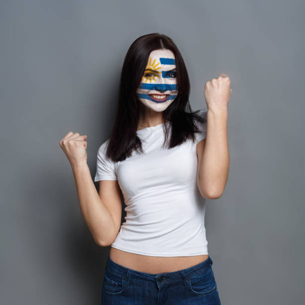 istock Young woman with Uruguay flag painted on her face 951059892