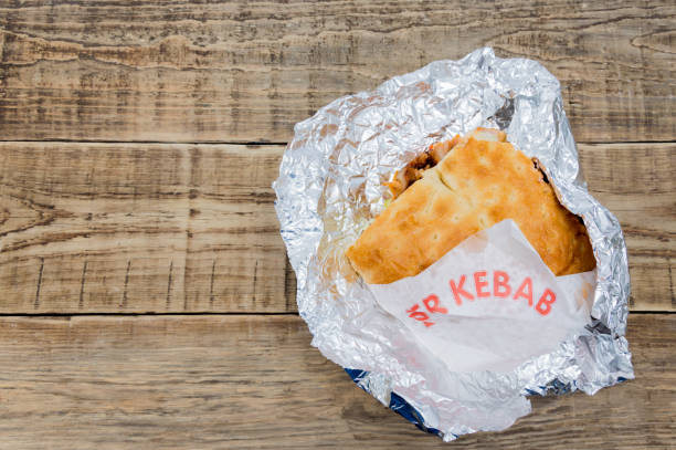 Turkish kebab on a wooden table wrapped in foil is copy space