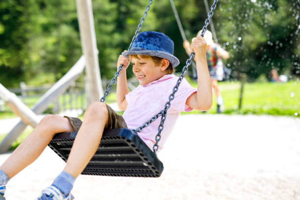 istock Funny kid boy having fun with chain swing on outdoor playground while being wet splashed with water 951060120