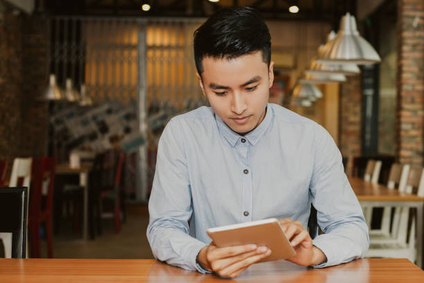 istock Serious Asian Man Sitting in Cafe and Using Tablet 951061814