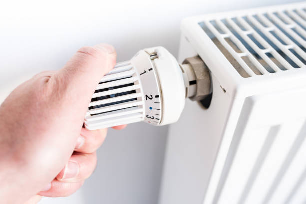 istock man adjusting temperature on thermostat on radiator 951073560