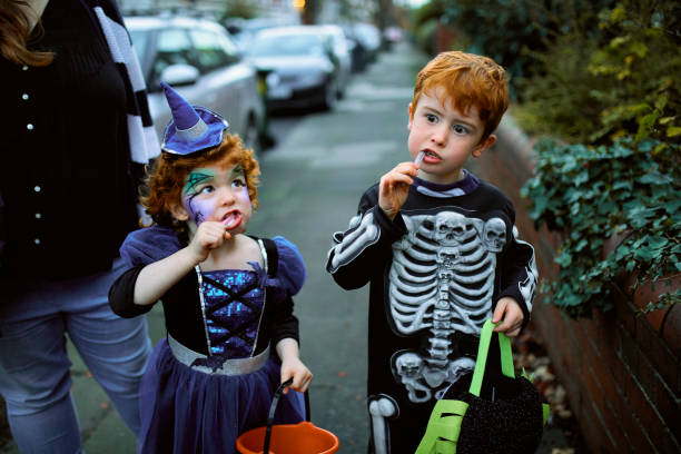 братья и сестры едят хэллоуин конфеты - child family event face paint стоковые фото и изображения
