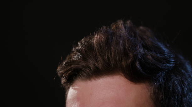 istock Man Touching his Hair Against a Black Background 951077852