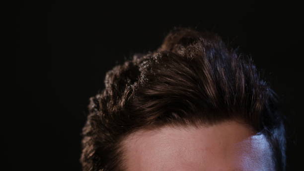 istock Man Touching his Hair Against a Black Background 951077906