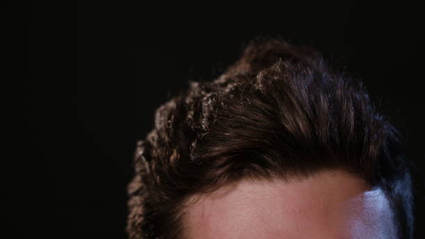 istock Man Touching his Hair Against a Black Background 951077942
