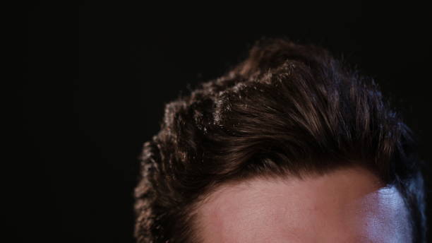 istock Man Touching his Hair Against a Black Background 951077986