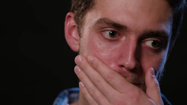 istock A Man Touching his Lips Against a Black Background 951078070